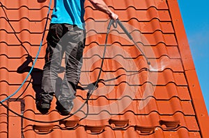 Worker cleaning metal roof with high pressure water