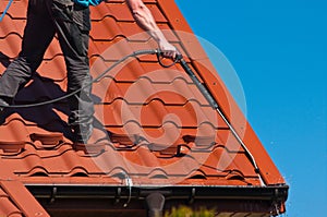 Worker cleaning metal roof with high pressure water