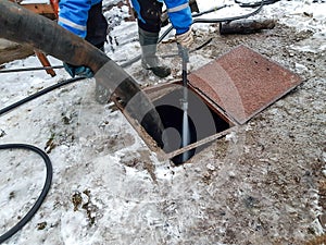 Worker cleaning the septic tank with water after emptying by sewage cleaner machinery