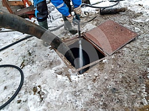 Worker cleaning the septic tank with water after emptying by sewage cleaner machinery