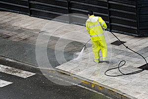 Worker cleaning the sidewalk with pressurized water