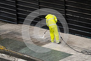 Worker cleaning the sidewalk with pressurized water