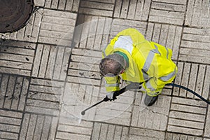 Worker cleaning a sidewalk with pressurized water photo