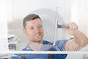 Worker Cleaning Soap Sud On Window With Squeegee photo