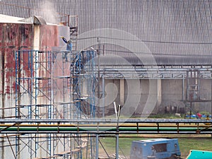 Worker cleaning storage tank by air pressure sand blasting.