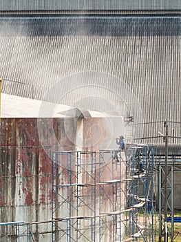 Worker cleaning storage tank by air pressure sand blasting.