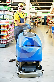 Worker cleaning store floor with machine