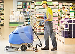 Worker cleaning store floor with machine