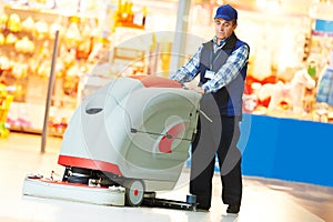 Worker cleaning store floor with machine