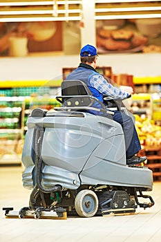 Worker cleaning store floor with machine