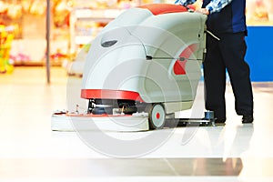 Worker cleaning store floor with machine