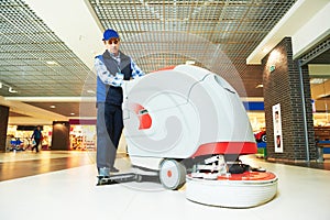 Worker cleaning store floor with machine