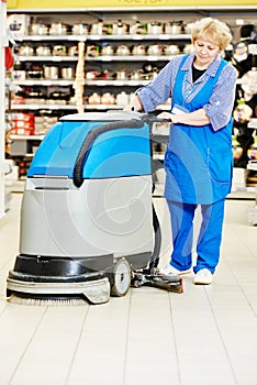 Worker cleaning store floor with machine