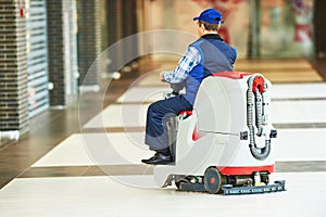 Worker cleaning store floor with machine