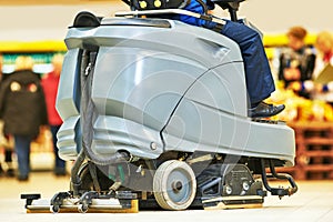 Worker cleaning store floor with machine