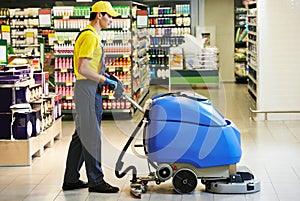 Worker cleaning store floor with machine