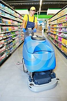 Worker cleaning store floor with machine