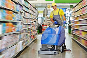 Worker cleaning store floor with machine photo