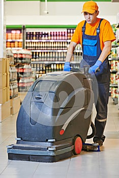 Worker cleaning store floor with machine