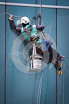 worker cleaning windows service on high rise building