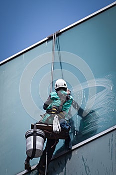 Worker cleaning windows service on high rise building