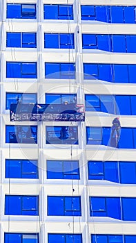 A worker cleans windows on a tall skyscraper office building