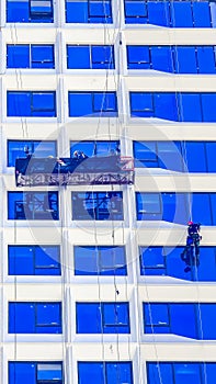 A worker cleans windows on a tall skyscraper office building