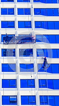 A worker cleans windows on a tall skyscraper office building