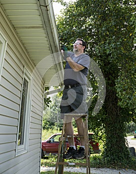 Worker Clearing Gutters Of Leaves & Sticks