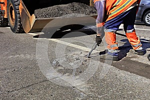 A worker clears a piece of asphalt with a pneumatic jackhammer in road construction photo