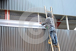 Worker climbing bamboo stair installation wiremesh and translucent louver in construction site