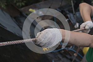 The worker is climbing on the house roof using the safety rope to recover old tar paper with a new one