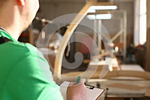 Worker with clipboard draws up order for production of furniture closeup