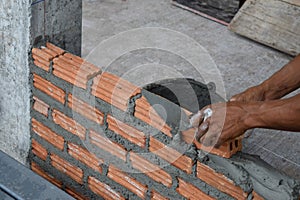 Worker in Close up of industrial bricklayer installing bricks and mortar cement brick