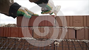 Worker in Close up of industrial bricklayer installing bricks and mortar cement brick on construction site. Worker