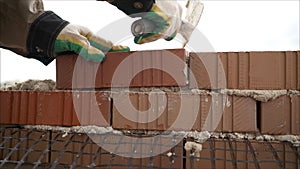 Worker in Close up of industrial bricklayer installing bricks and mortar cement brick on construction site. Worker builds a house