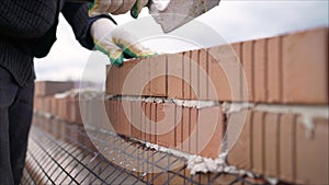 Worker in Close up of industrial bricklayer installing bricks and mortar cement brick on construction site. Worker builds a house