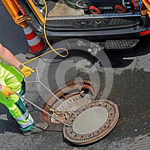 Worker closes a manhole cover in the street