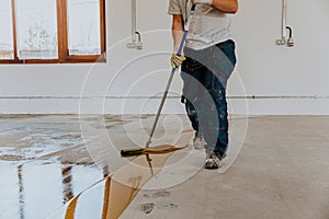 Worker, coating floor with self-leveling epoxy resin in industrial deposit