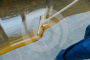 Worker, coating floor with self-leveling epoxy resin in industrial deposit