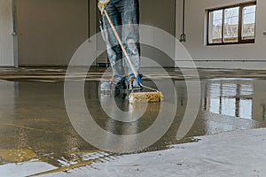 Worker, coating floor with self-leveling epoxy resin in industrial deposit