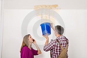 Worker Collecting Water In Bucket From Ceiling