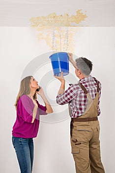 Worker Collecting Water In Bucket From Ceiling