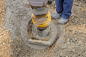 Worker compacting the sand bedding with mechanical rammer
