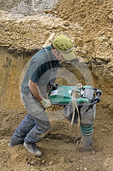 Worker compacting sand with vibrating plate tamper