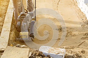 worker compresses sand in blind area around building with special working tool & x28;tamping machine or vibratory plate