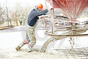 Worker during concrete pouring into formwork