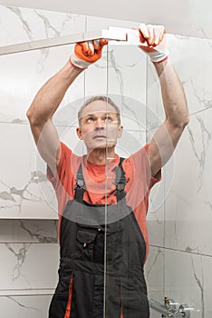 The worker is connecting the walls of the shower enclosure with a metal bar