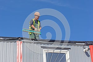 Worker at the construction site cleans the roof
