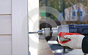Worker at construction site drills wall drilling machine